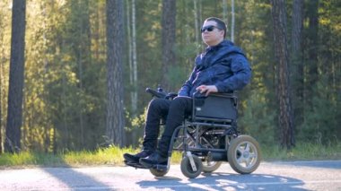 Bir orman arka planı Engelli adam yeti tekerlekli sandalyede oturuyor
