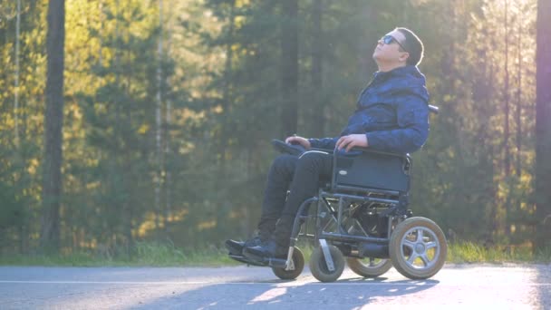 Pessoa deficiente em uma cadeira de rodas está se divertindo e natureza circundante — Vídeo de Stock