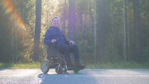 Sonriente hombre con discapacidad física sentado en una silla de ruedas motorizada al aire libre — Vídeos de Stock