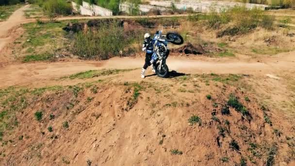 Un motard se tient debout avec sa moto sur une colline. Portrait . — Video