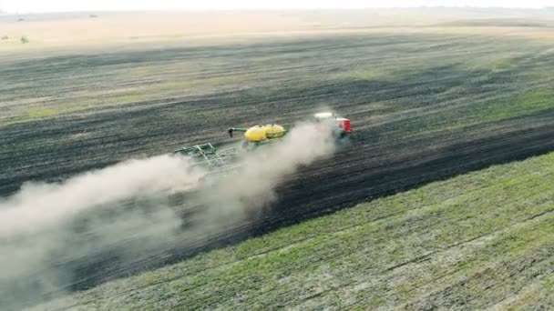 Een trekker werkt op een groen veld. — Stockvideo