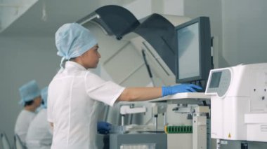 Kadın yeni kan örnekleri bir raf bir klinikte özel tıbbi makinenin içine koyar. HD.