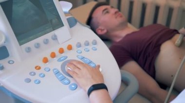 Bir doktor hasta mide tarar. Bir doktor bir klinik bir erkek hasta ultrasonografi gerçekleştirir.