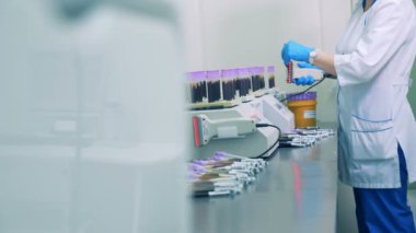 Bir hemşire kan örnekleri şişe üzerinde barkod tarar, sonra bunları özel bir raf yerleştirir. HD.