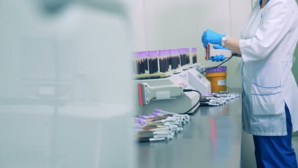 Une infirmière scanne les codes à barres sur des bouteilles d'échantillons de sang, puis les place sur un support spécial. HD .