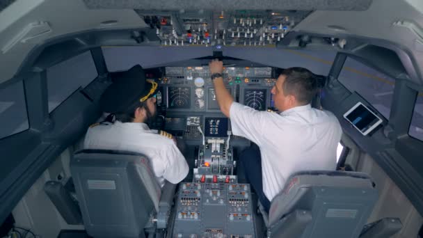 Dos pilotos están sentados en una cabina de avión y discutiendo algo — Vídeo de stock