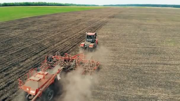 Un trattore lavora su un grande campo, coltivando terreno. 4K. Aerea . — Video Stock