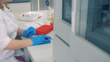 Bir laboratuvar çalışan bilgisayar başında çalışırken bir santrifüj kan tüplerini kontrol edilir.