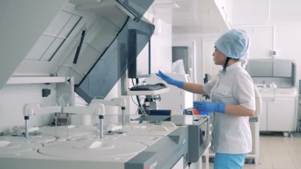 Científica mujer analiza muestras de sangre en una sala de laboratorio utilizando equipos modernos . — Vídeos de Stock