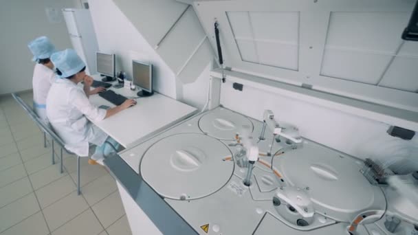 L'équipement spécial travaille dans une salle de laboratoire, tandis que les infirmières s'assoient aux ordinateurs. 4K . — Video