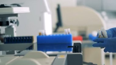 Bir hemşire tıbbi bir makine ile modern bir laboratuvar tüplerde yükler, yakın çekim.