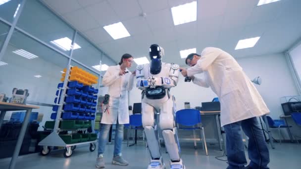 Two engineers check robot and fix it. — Stock Video