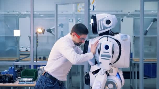 Um homem empurra um cyborg duas vezes. Homem trabalhador teste robôs equilíbrio, empurrando-o com força . — Vídeo de Stock