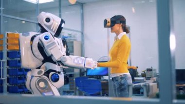 Bir kadın robotlar eller alır ve etrafına bakıyor.