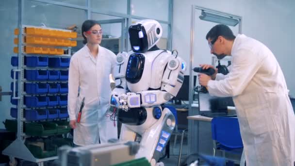 Arbetstagare reparera en robot i ett laboratorium rum. — Stockvideo