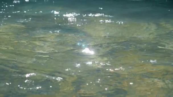 きれいに水 babbles 演じ、クローズ アップ。それからは反射の光で水面. — ストック動画