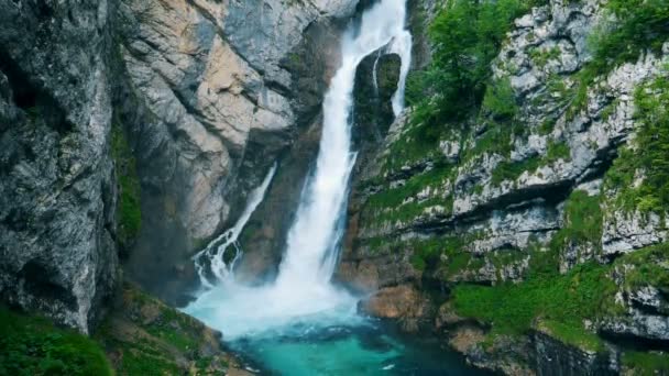 Una gran cascada salpica. La cascada fluye hacia abajo y entra en el río en el cañón . — Vídeos de Stock