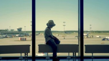 Çocuk oturur ve uçaklar görünüyor.