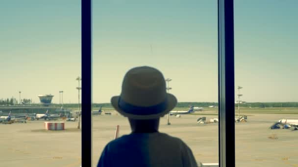 공항에서 아이입니다. 창문을 통해 공항 활주로에서 보이는 소년. — 비디오