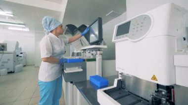 Kadın türleri bir monitörde bir tıbbi ekipman bir laboratuvar odasında çalışırken. 4k.