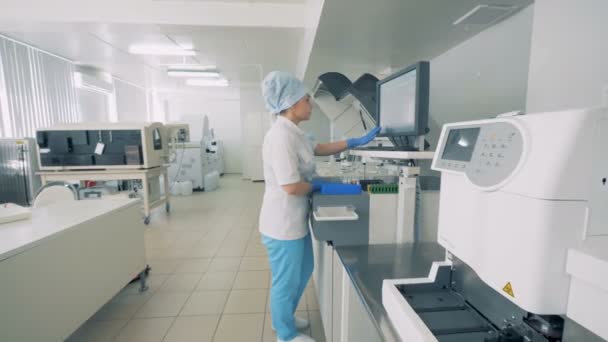 Una mujer trabaja en una sala de laboratorio con equipo . — Vídeos de Stock