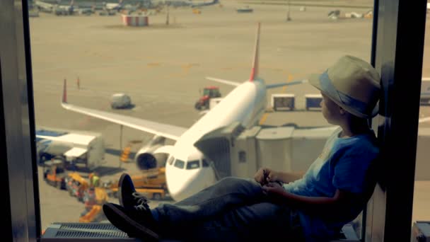 Viajero joven, niño sentado en una ventana en un aeropuerto esperando un viaje . — Vídeos de Stock