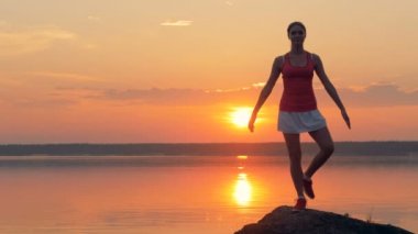 Bir kız bir gün batımı arka plan üzerinde meditasyon.