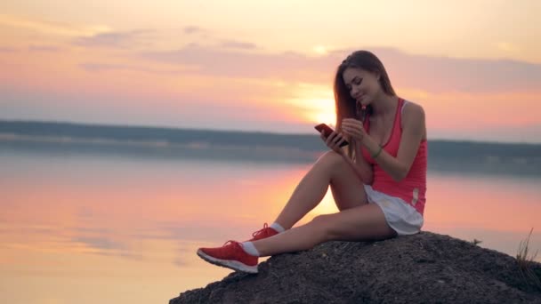 Een vrouw maakt gebruik van haar telefoon, terwijl rusten. — Stockvideo