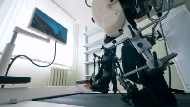 Primer plano de las piernas del hombre en los lazos de una máquina de entrenamiento durante los ejercicios de caminar. Robótica médica electrónica para rehabilitación . — Vídeo de stock