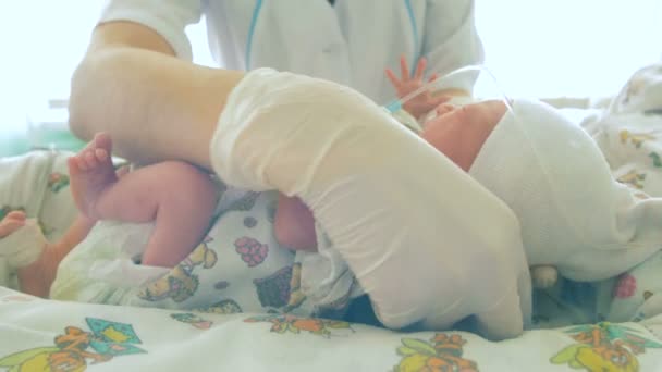 Orvos elhelyezés egy kisgyermek az ágyra, és belemerül a takaró — Stock videók
