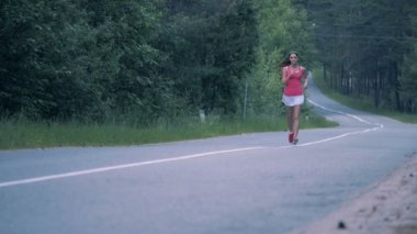 Ormanın içinde yol boyunca iyi görünümlü Bayan koşu