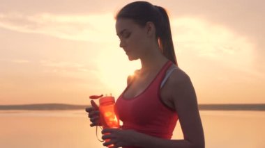 Oldukça genç bir kız bir şişe açılış ve ondan içme yakın çekim