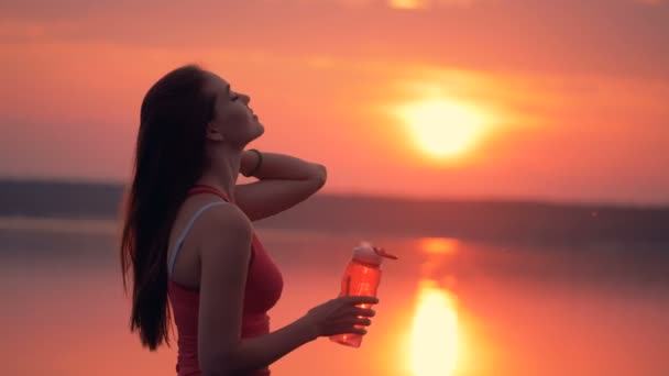 Jovencita está tirando su pelo largo y bebiendo de una botella — Vídeos de Stock