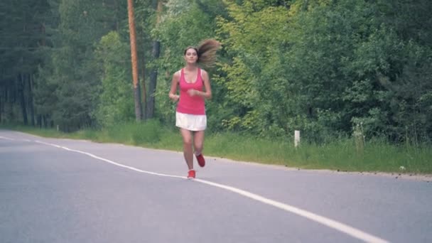 Лесная дорога с великолепной женщиной, бегущей вдоль нее — стоковое видео