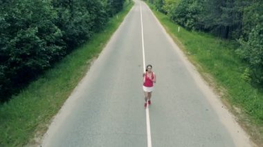 Odak ince, güzel bir kadın sokakta koşu uzak hareket ediyor. Hava.