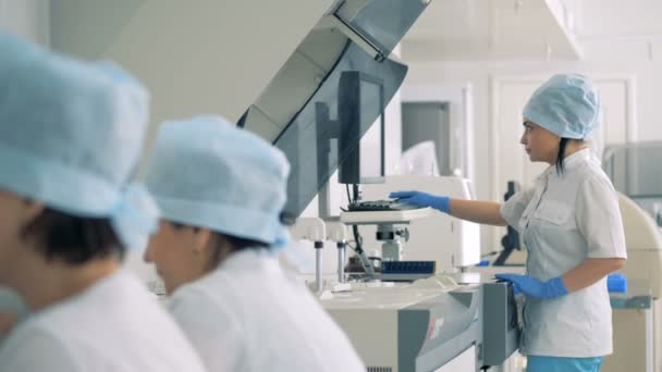 女性医師が臨床化学分析装置の機能制御します。 — ストック動画