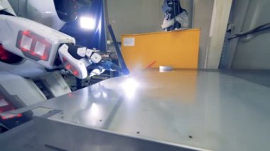 Yakın çekim, beyaz robot kaynak aygıtları kullanır. Özel robot sac kaynak bir fabrikada çalışıyor.