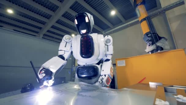 Μια droid λειτουργεί με μηχανή συγκόλλησης, κοντινό. Ένα ρομπότ συγκολλήσεις ένα φύλλο μετάλλου σε ένα εργοστάσιο. — Αρχείο Βίντεο