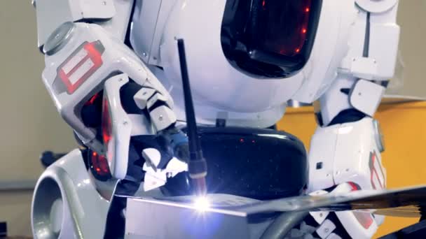 Промышленный человекоподобный робот работает с сварочной машиной, крупным планом . — стоковое видео