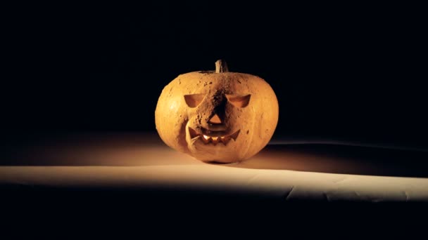 The light in a room with a halloween pumpkin is getting switched off and on. Halloween pumpkin in dark. — Stock Video