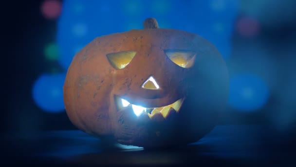 Linterna Jack-o-Lantern radiante ubicada en una habitación oscura con una fiesta en ella. Feliz concepto de calabaza de Halloween . — Vídeo de stock