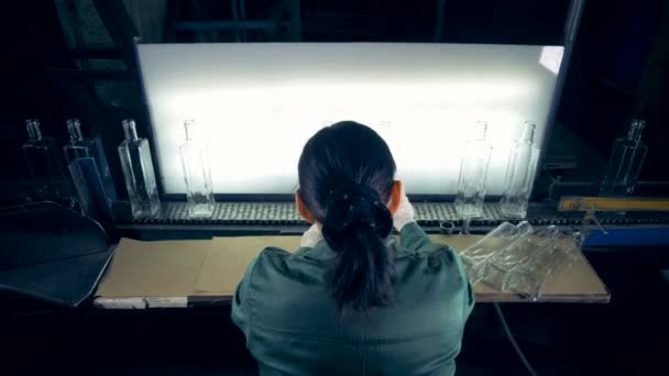 Kvinnlig arbetstagare kontrollerar flaskor, kasta ut dåliga, på en fabrik. 4k. — Stockvideo