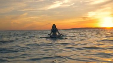 Okyanusta istirahat kadın. Sporcumuz onu sörf tahtası üzerinde bir yolculuktan sonra derin derin düşünür.