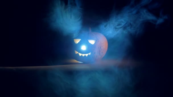 Dark room with clouds of mist and a glowing jack-o-lantern. Scary carved halloween pumpkin. — Stock Video