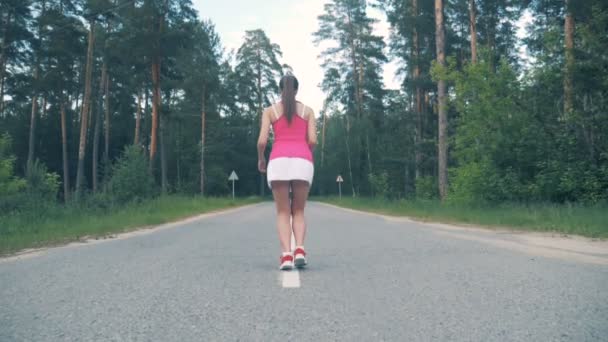 Ung kvinna börjar löpa längs vägen. Kvinnliga idrottare jogging. — Stockvideo