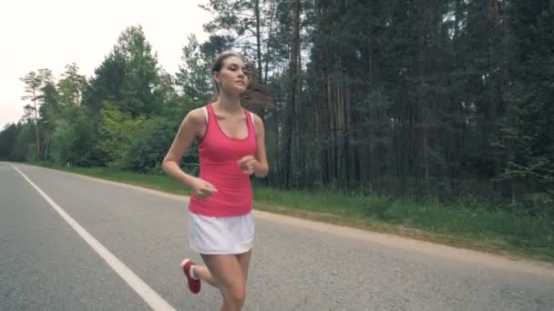 Lesní cesta s mladou dámou, která běží podél ní. Zdravá štíhlá Mladá sportovkyně běží. — Stock video