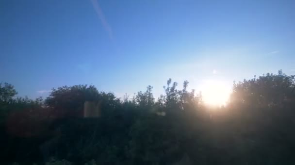 Paisagem natural ao pôr do sol vista através de uma janela de transporte em movimento — Vídeo de Stock