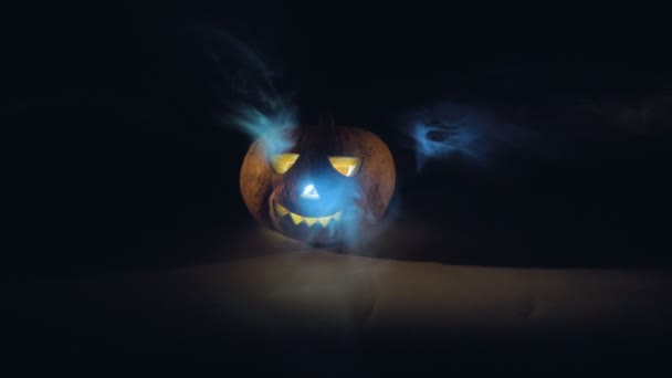 Dekorativer Halloween-Kürbis umgeben von Rauch und Dunkelheit. Gruselig geschnitzter Halloween-Kürbis. — Stockvideo