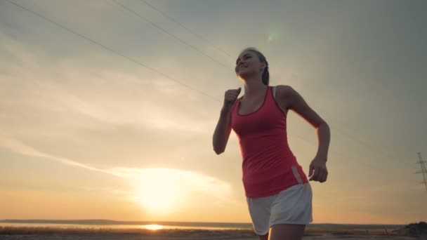 Mujer delgada sonríe y corre al atardecer. concepto de estilo de vida saludable . — Vídeo de stock