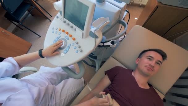 Il dottore sta eseguendo una procedura ad ultrasuoni su un uomo — Video Stock